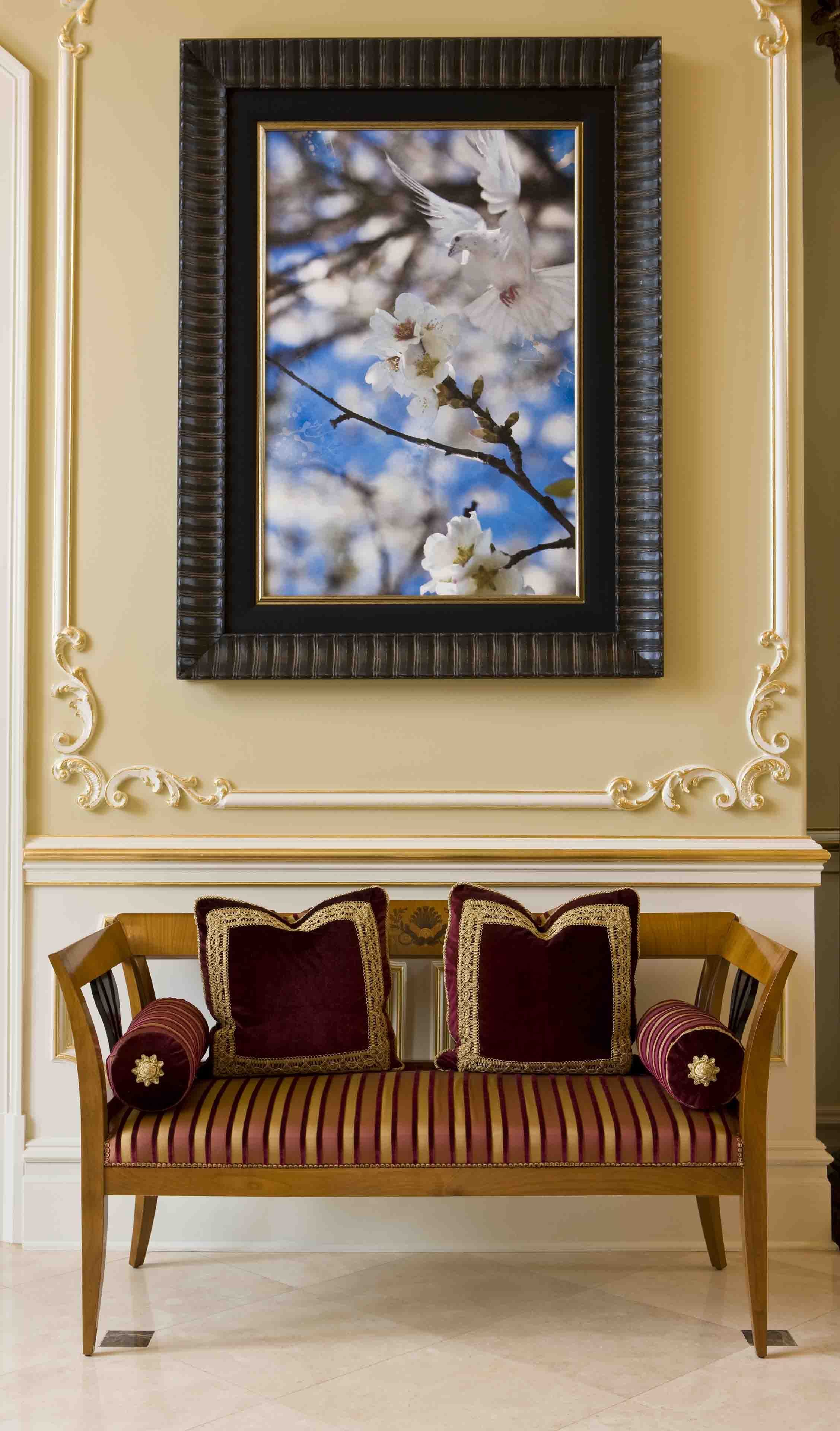 Classical seating with burgundy and gold pillows and painting of a white bird